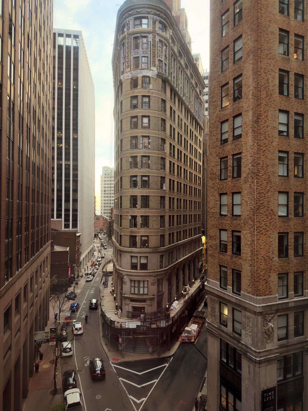 An elevated view of a narrow city street and a rounded historic building between taller towers.