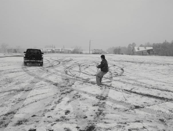 Someone is pulled behind a truck on a snowboard.