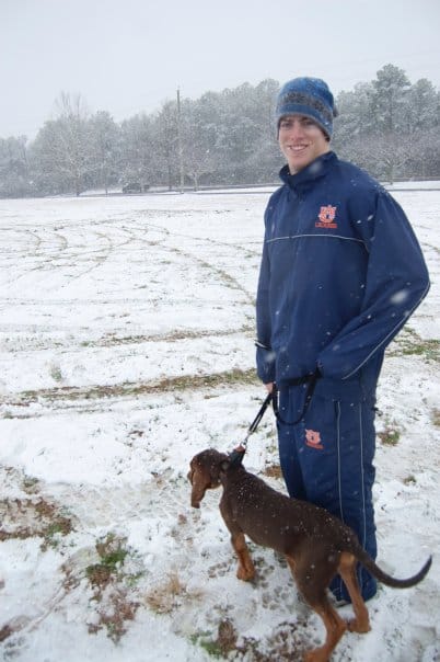 Kenny poses with a dog in the snow.