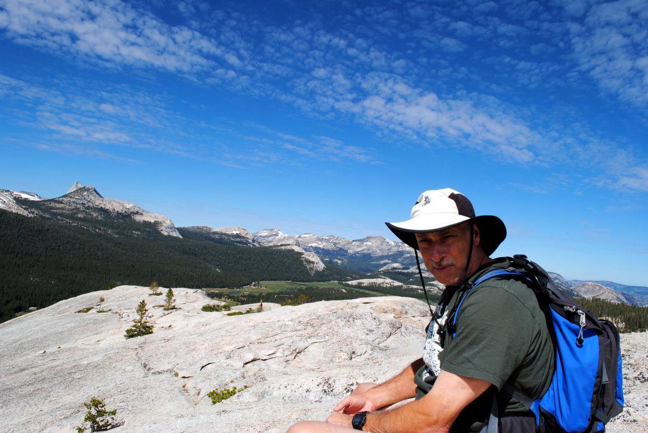 Dad with a wide-brimmed hat and backpack on top of Lembert Dome.