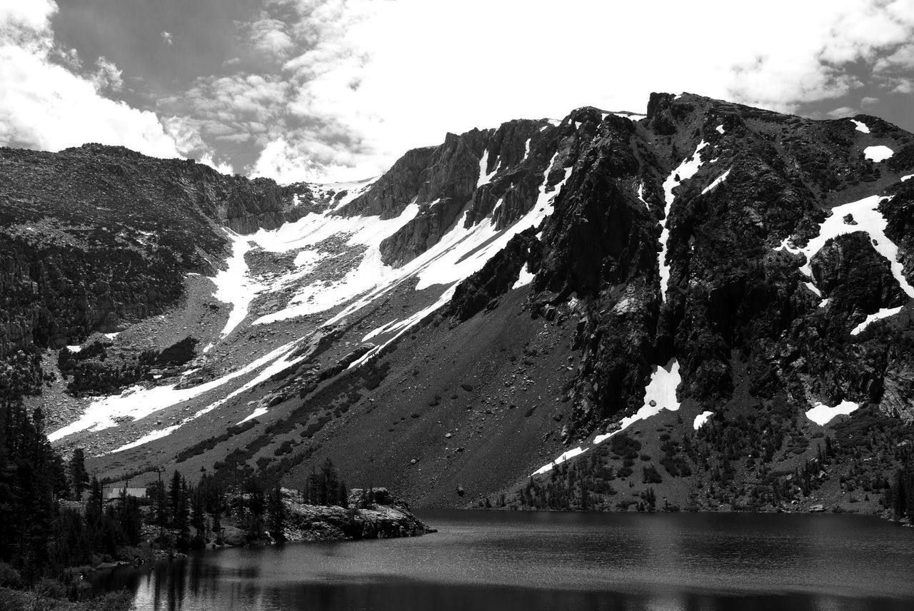 Black and white photo of a lake surrounded by mountains.