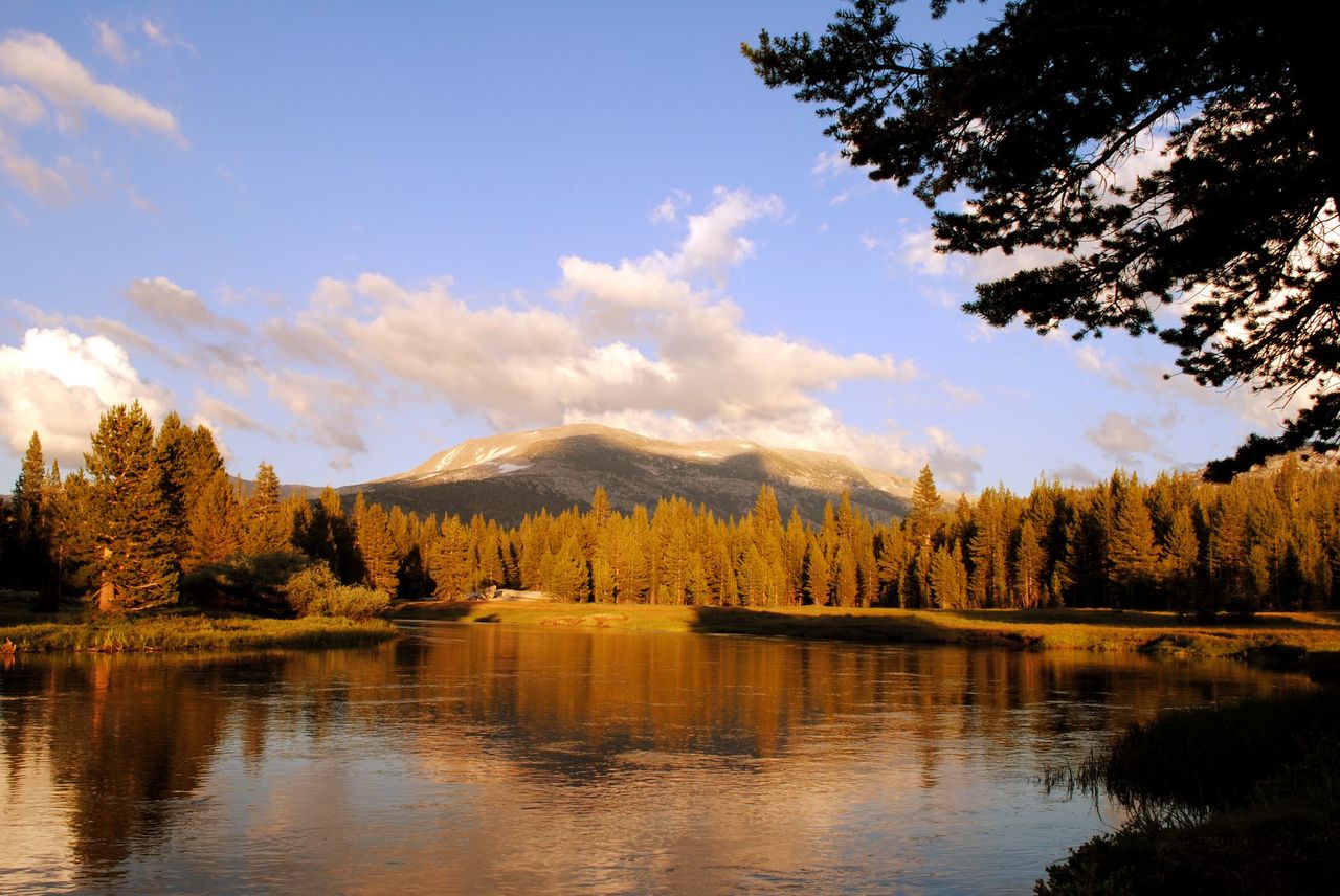 Picture taken at sunset. It has a river with trees in the distance and a mountain in the background.