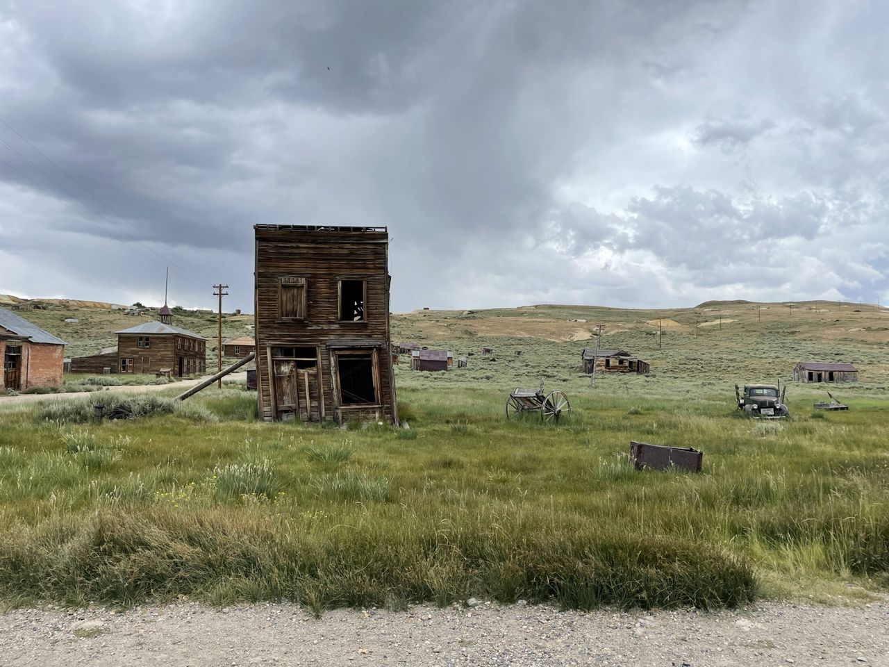 An old building in a field has a support beam holding it up.