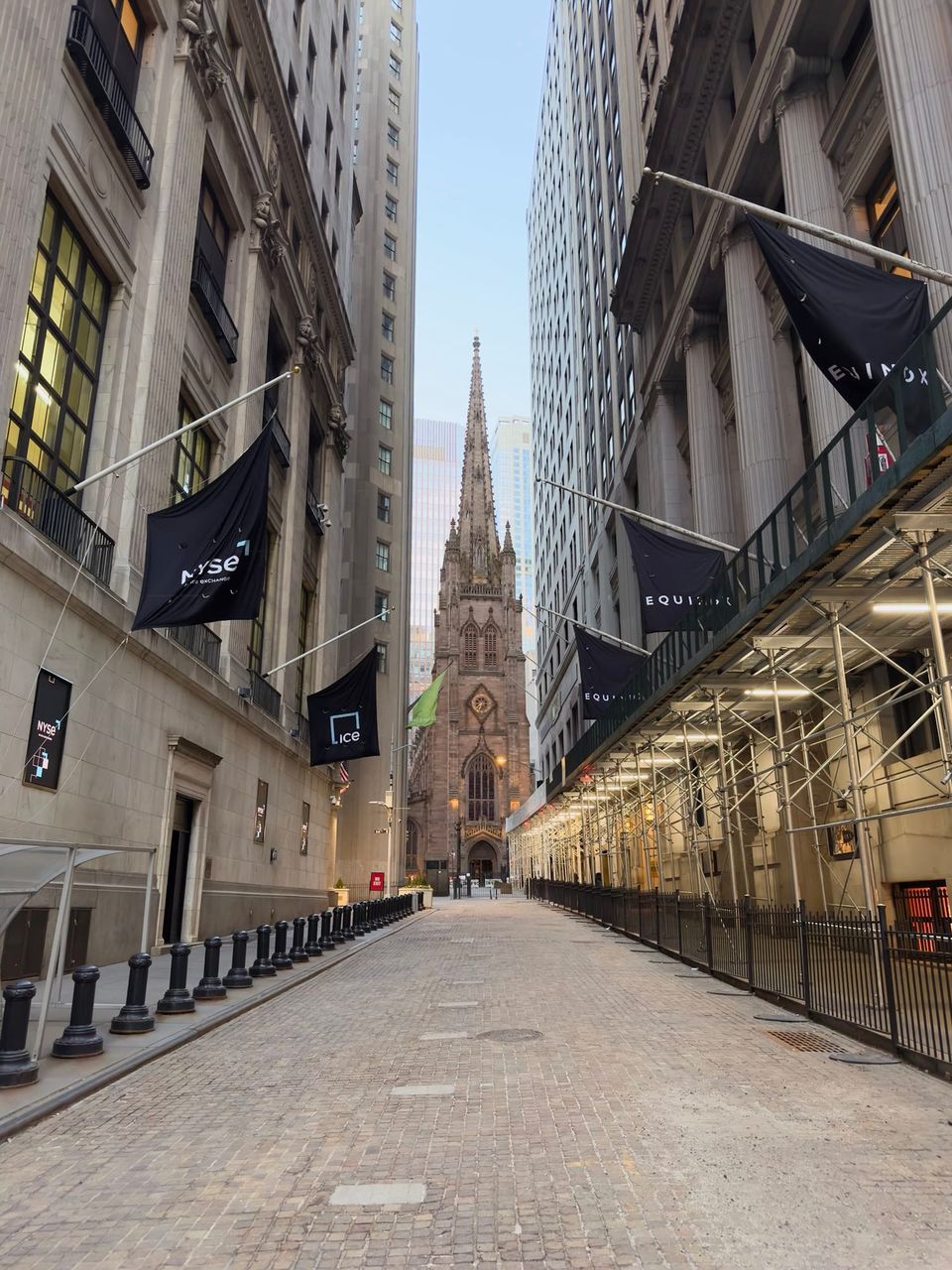 Cobblestone street lined with NYSE and Equinox banners leading to Trinity Church