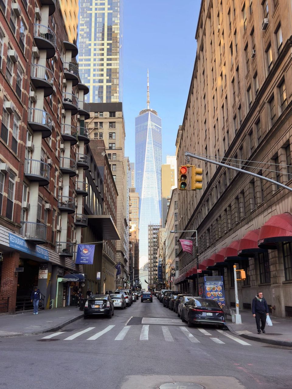 One World Trade Center framed at the end of a street lined with brick buildings